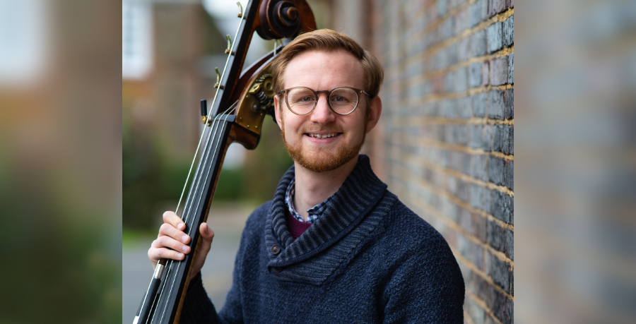 RPO Player Joe Cowie holding his double bass and smiling at the camera