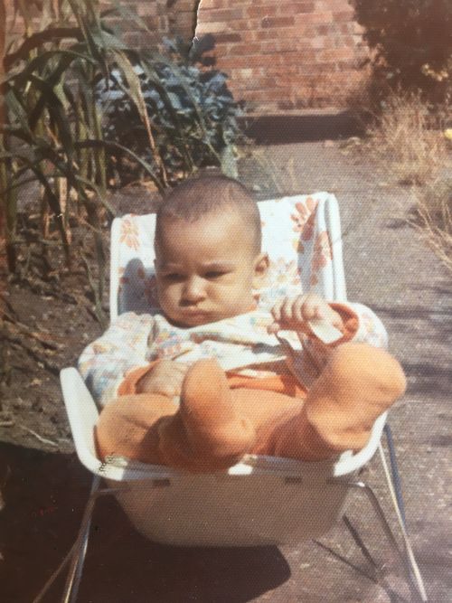 Composer Des Oliver as a baby. He is sitting in a baby bouncer chair in a garden. 