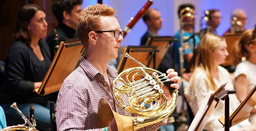 RPO Player Alexander Edmundson playing the horn in rehearsal.