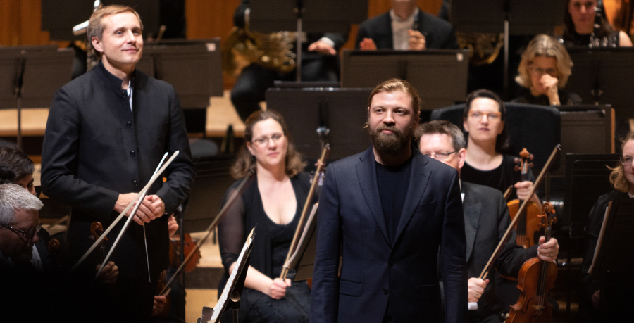 Vasily Petrenko and Denis Kozhukhin standing on stage to receive applause with the Orchestra behind them.