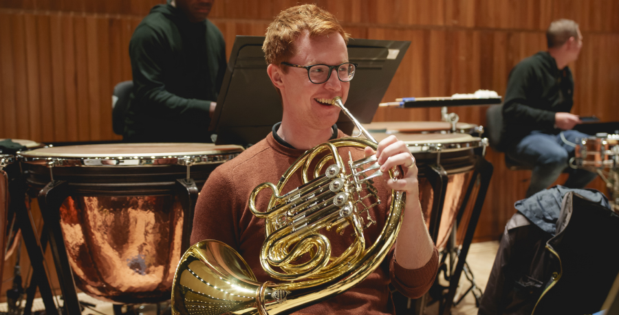 RPO Player Finlay Bain playing the horn in rehearsal.