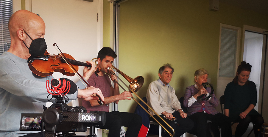 An image of a RPO Resound session with a male violinist and male trombonist with 2 members in the session all sitting down