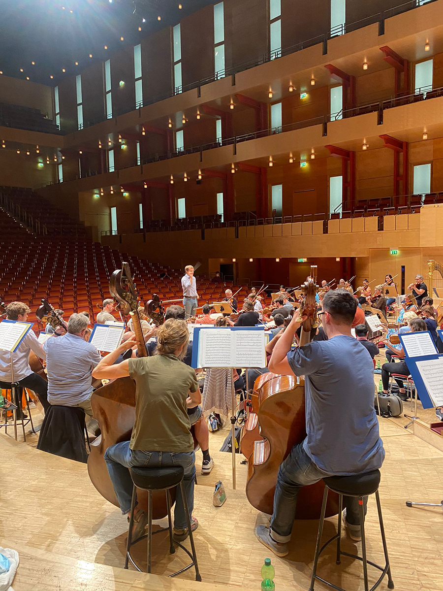 An image of Vasily Petrenko conducting the RPO on stage, the view is from the point-of-view of the cellos