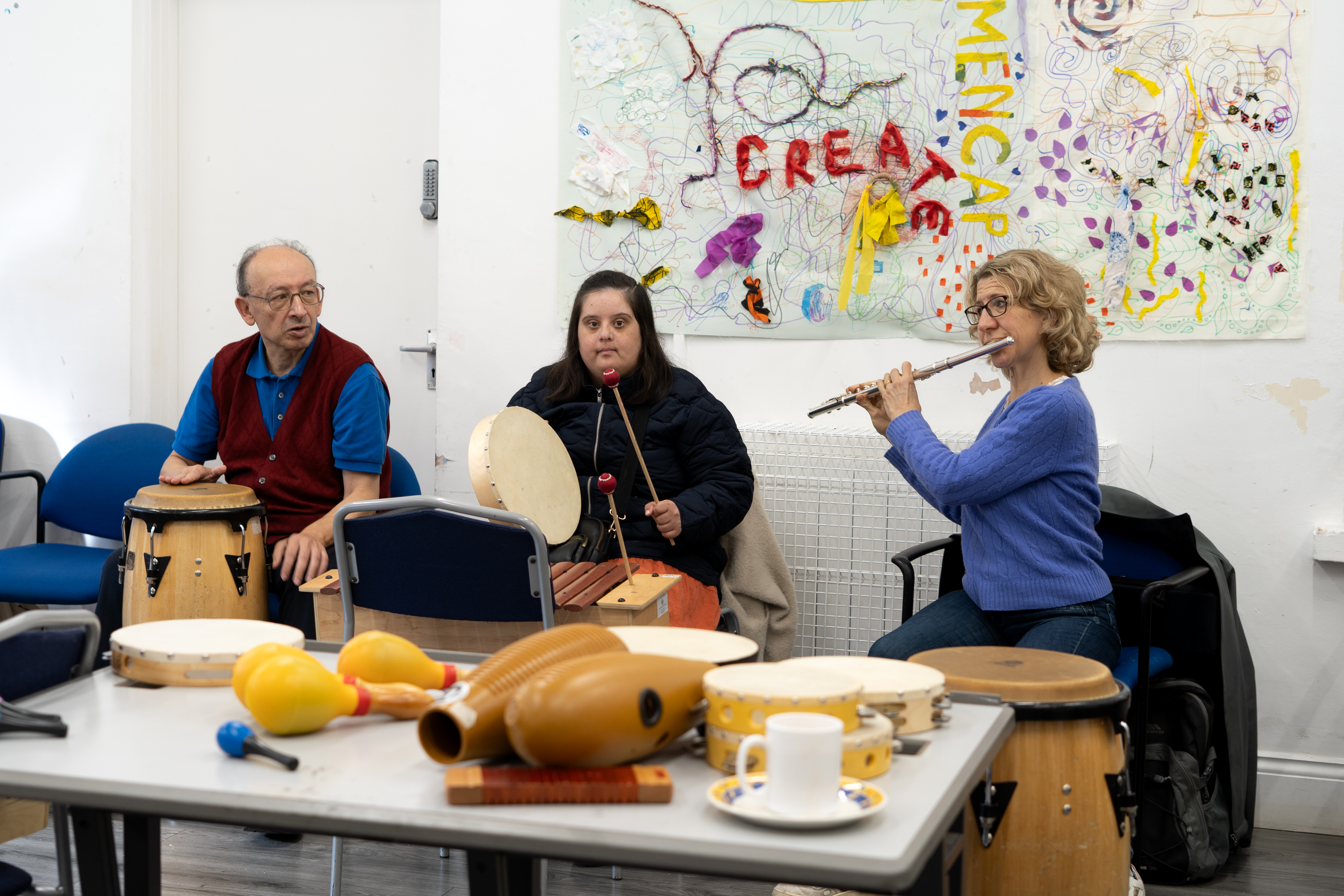 Participants playing percussion instruments alongside RPO musician playing the flute