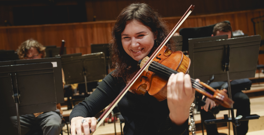 RPO Player Ugne Tiškutė playing her viola in rehearsal while smiling