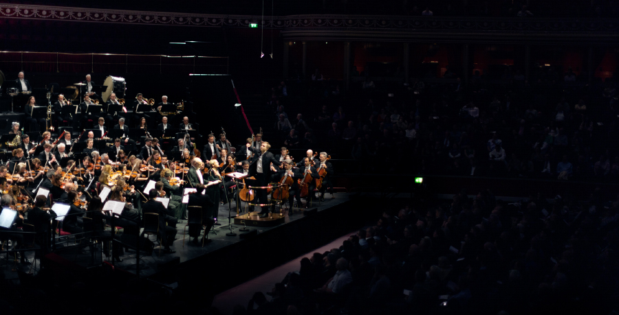 Vasily Petrenko conducting the Royal Philharmonic Orchestra in concert at the Royal Albert Hall, with the audience in darkness to their right