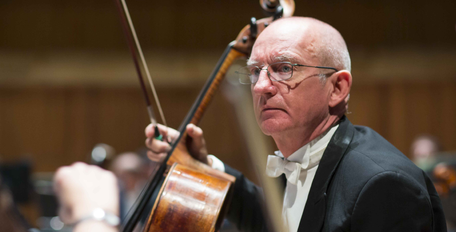 RPO Player William Heggart holding his cello in concert attire.