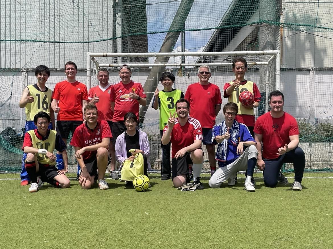 RPO players and Tokyo Metropolitan Symphony Orchestra musicians in football gear posing in front of a goal