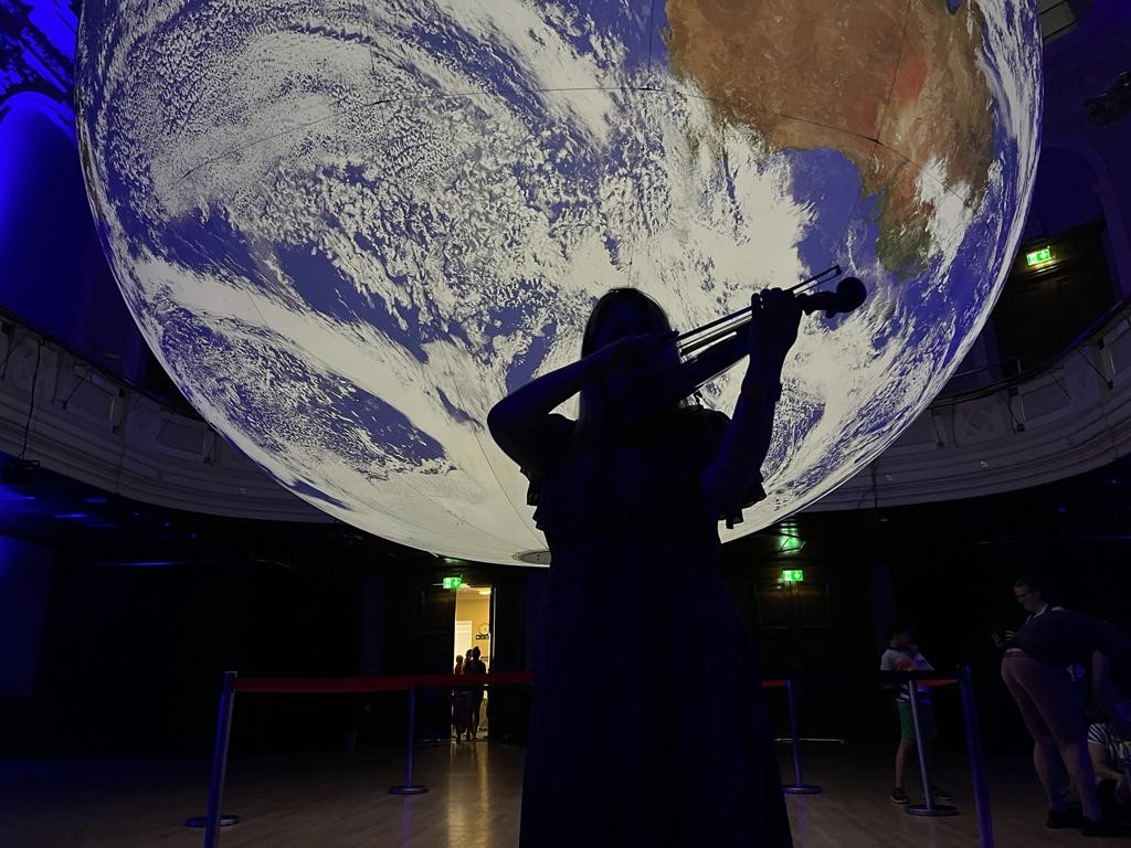 The Reading Gaia installation, with a violinist silhoutted against the Earth