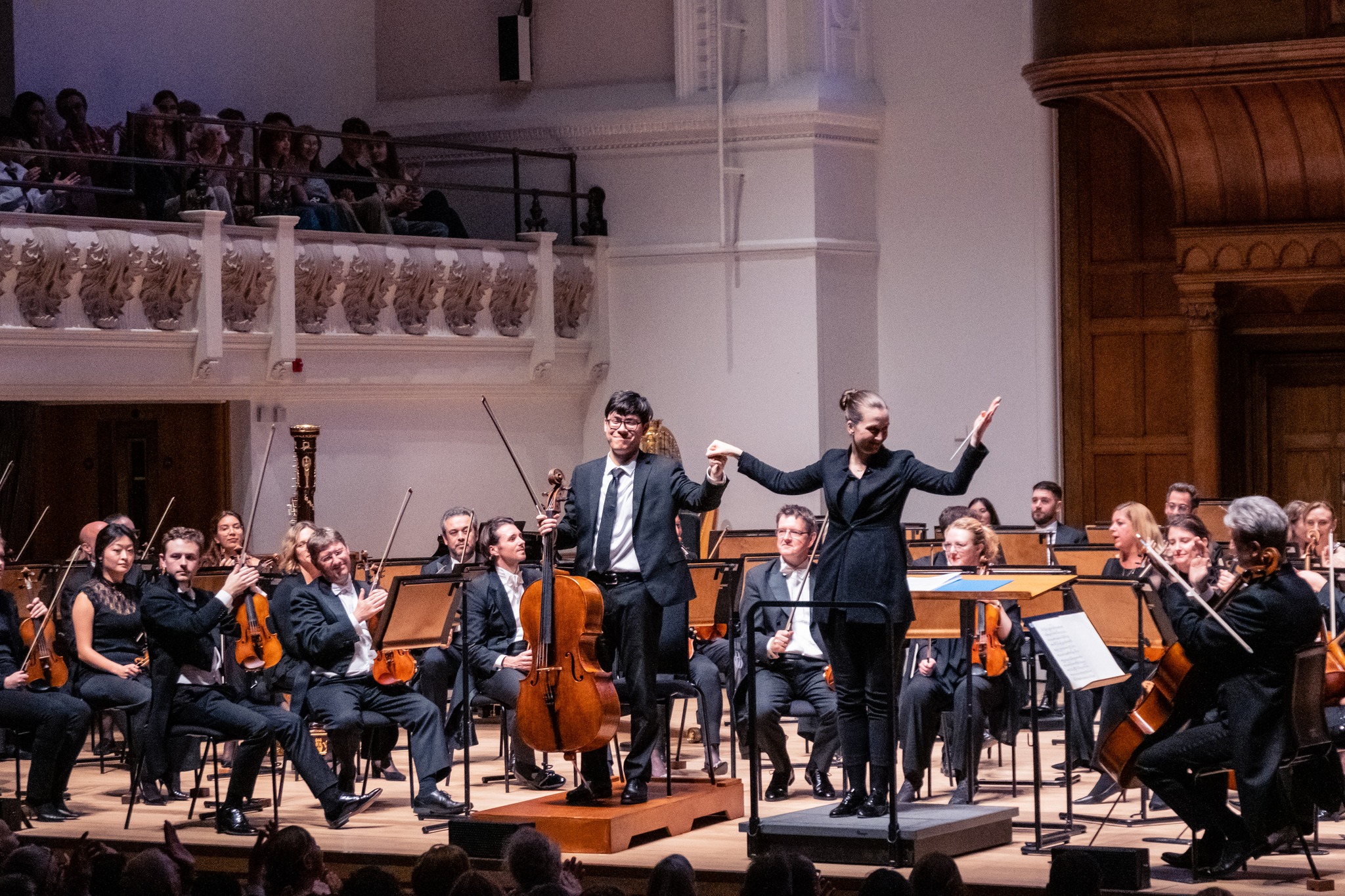 Cellist Zlatomir Fung and conductor Elena Schwarz receiving applause on stage at Cadogan Hall