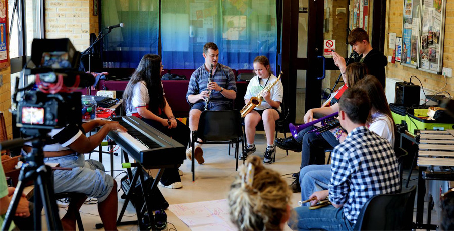 Young people and orchestra players sitting in a circle together with their instruments