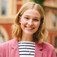 Minnie Elliott in a striped shirt and pink blazer outside the Royal Albert Hall