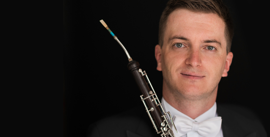A portrait photo of Patrick Flanaghan in concert dress holding his cor anglais