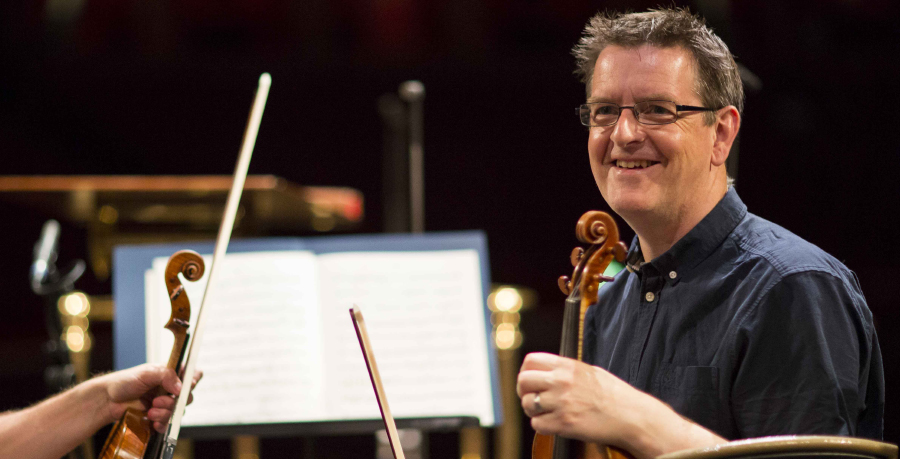 RPO Player Andrew Storey smiling whilst holding his violin.