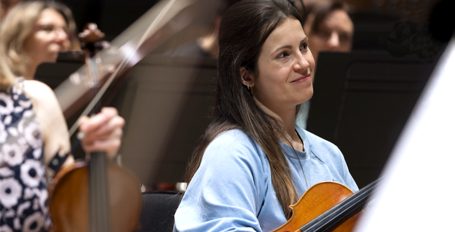 Inês Delgado holding her violin in rehearsal and smiling