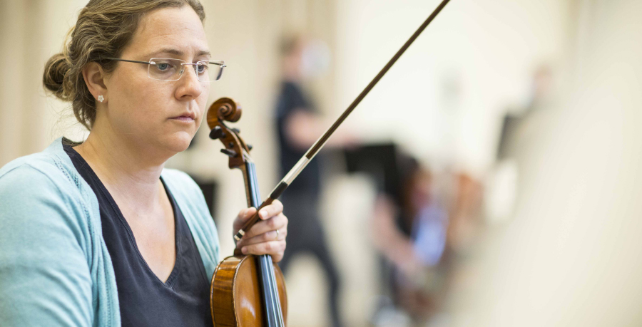 RPO Player Jennifer András holding her violin in rehearsal.