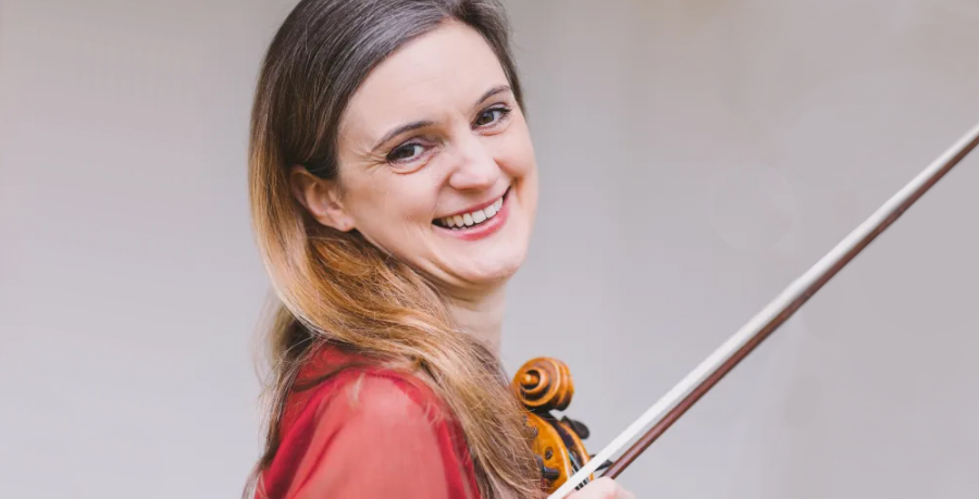 RPO Player Judith Templeman smiling whilst holding her violin.