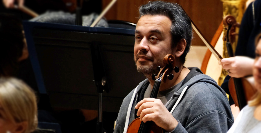 RPO Player Manuel Porta holding his violin in rehearsal.
