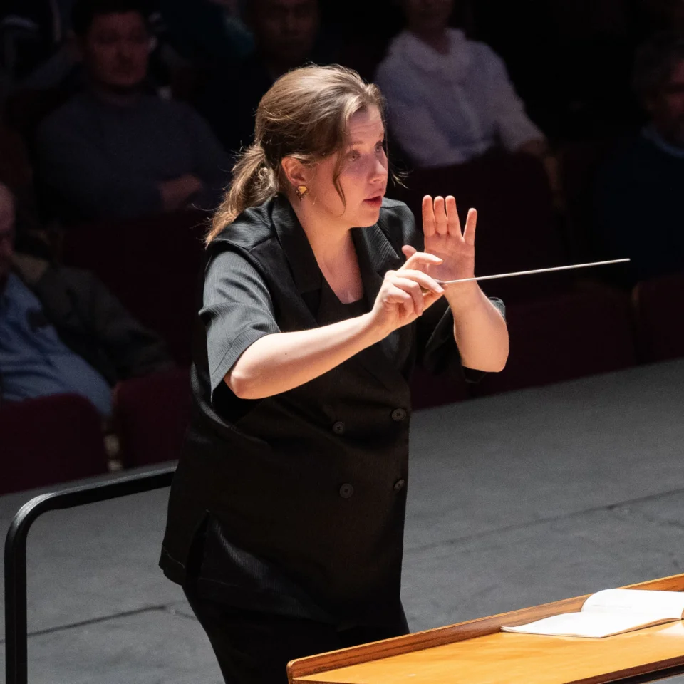 Conductor Emilia Hoving stands in concert, with baton in hand