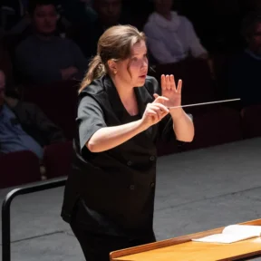 Conductor Emilia Hoving stands in concert, with baton in hand