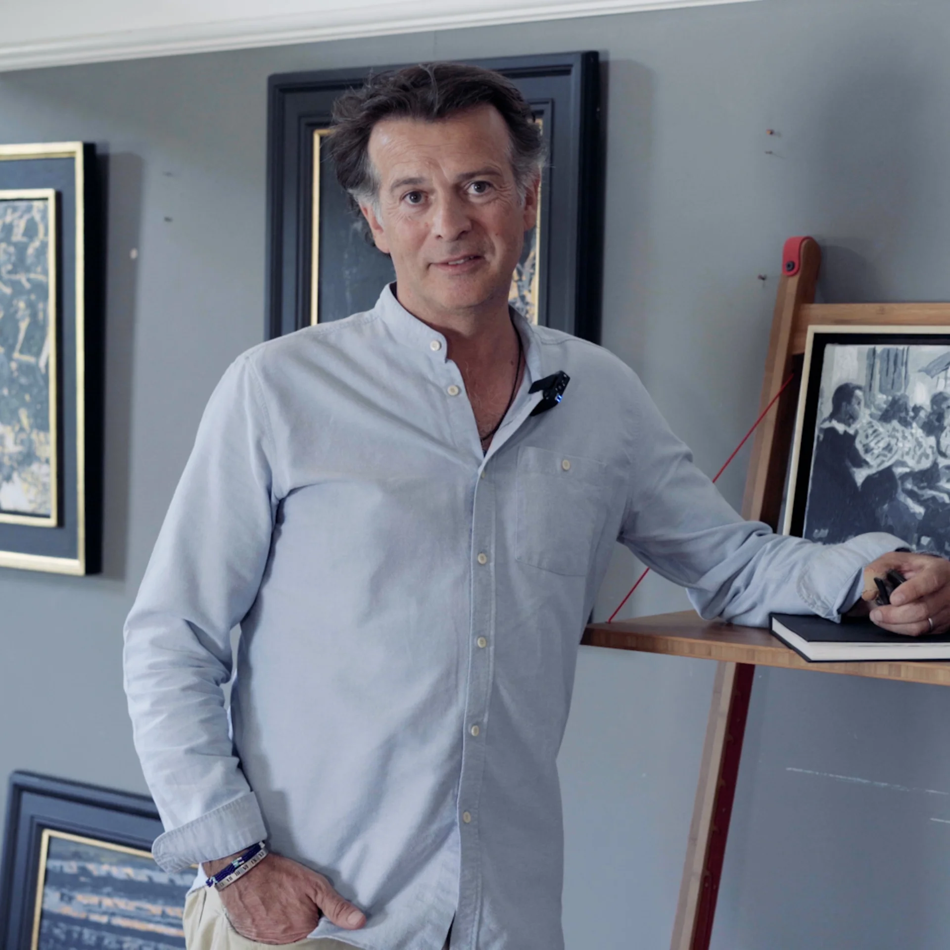 Jeremy Houghton posing by paintings of the Orchestra in his studio gallery