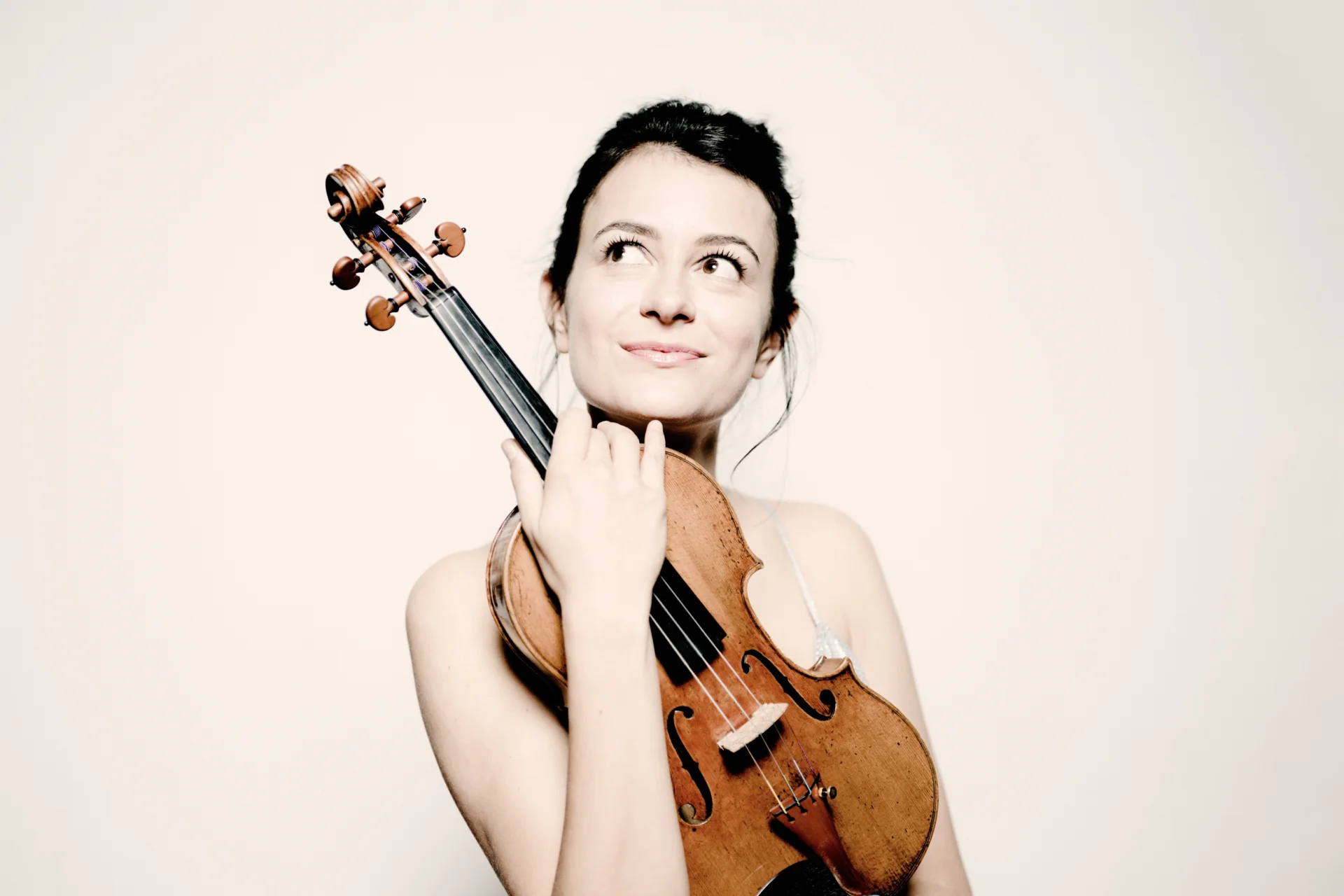 Liya Petrova holding her violin and looking up to the left