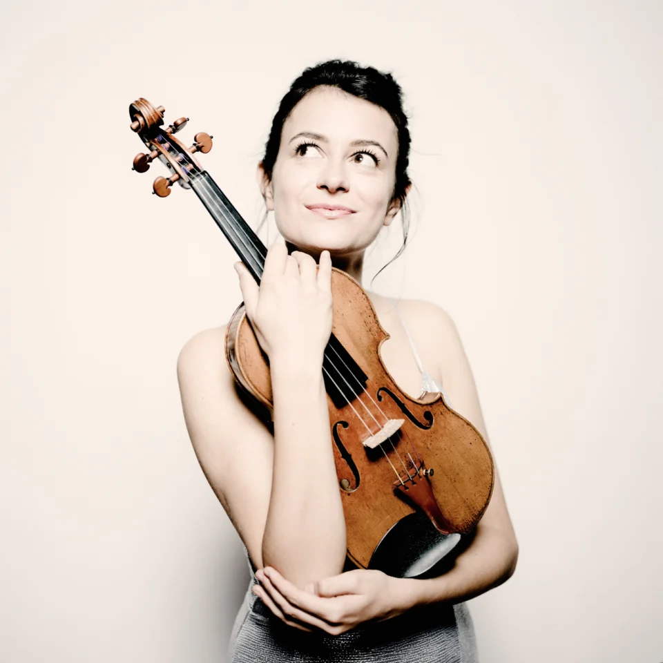 Liya Petrova holding her violin and looking up to the left