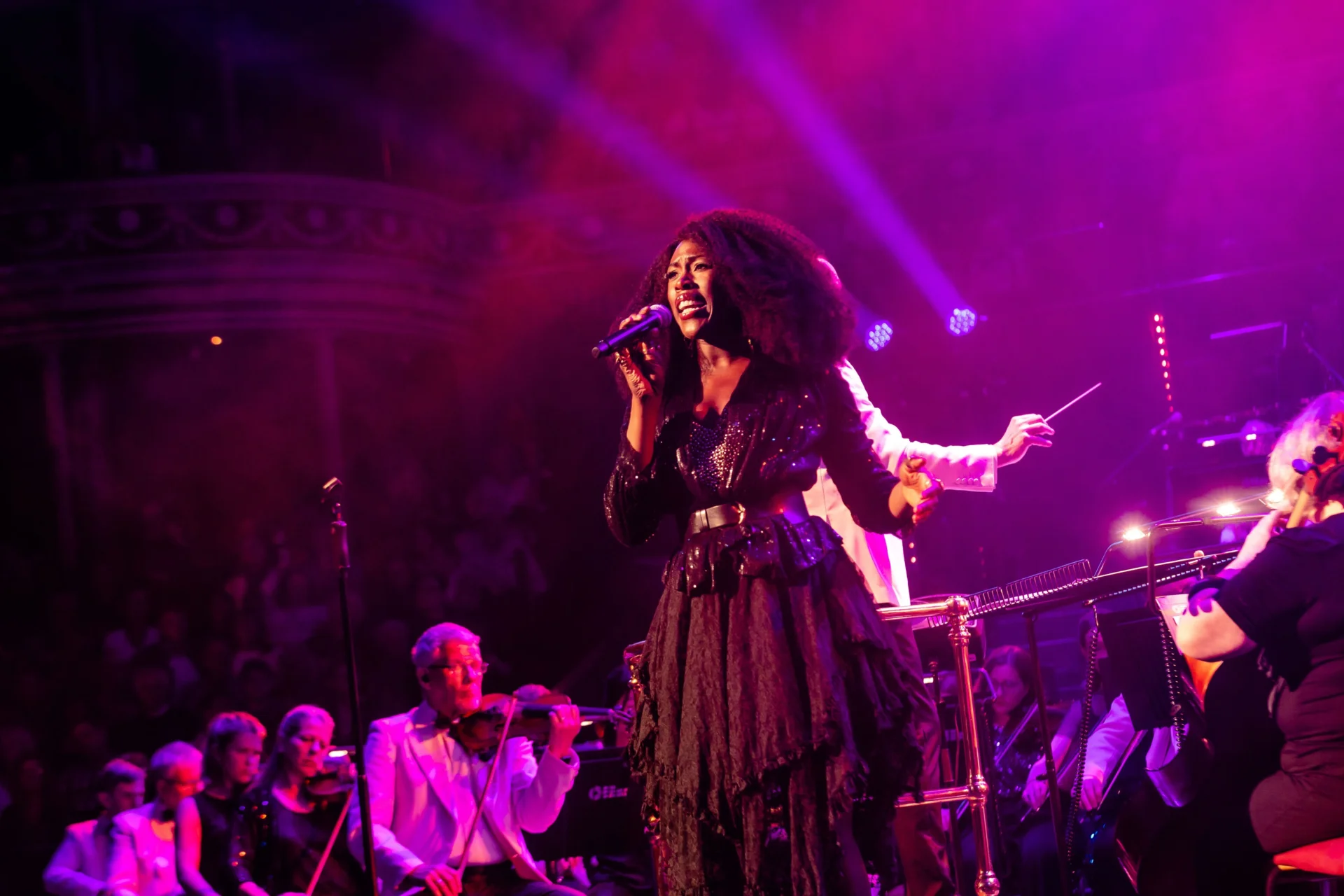 Gloria Onitiri stands singing in front of the Royal Philharmonic Orchestra