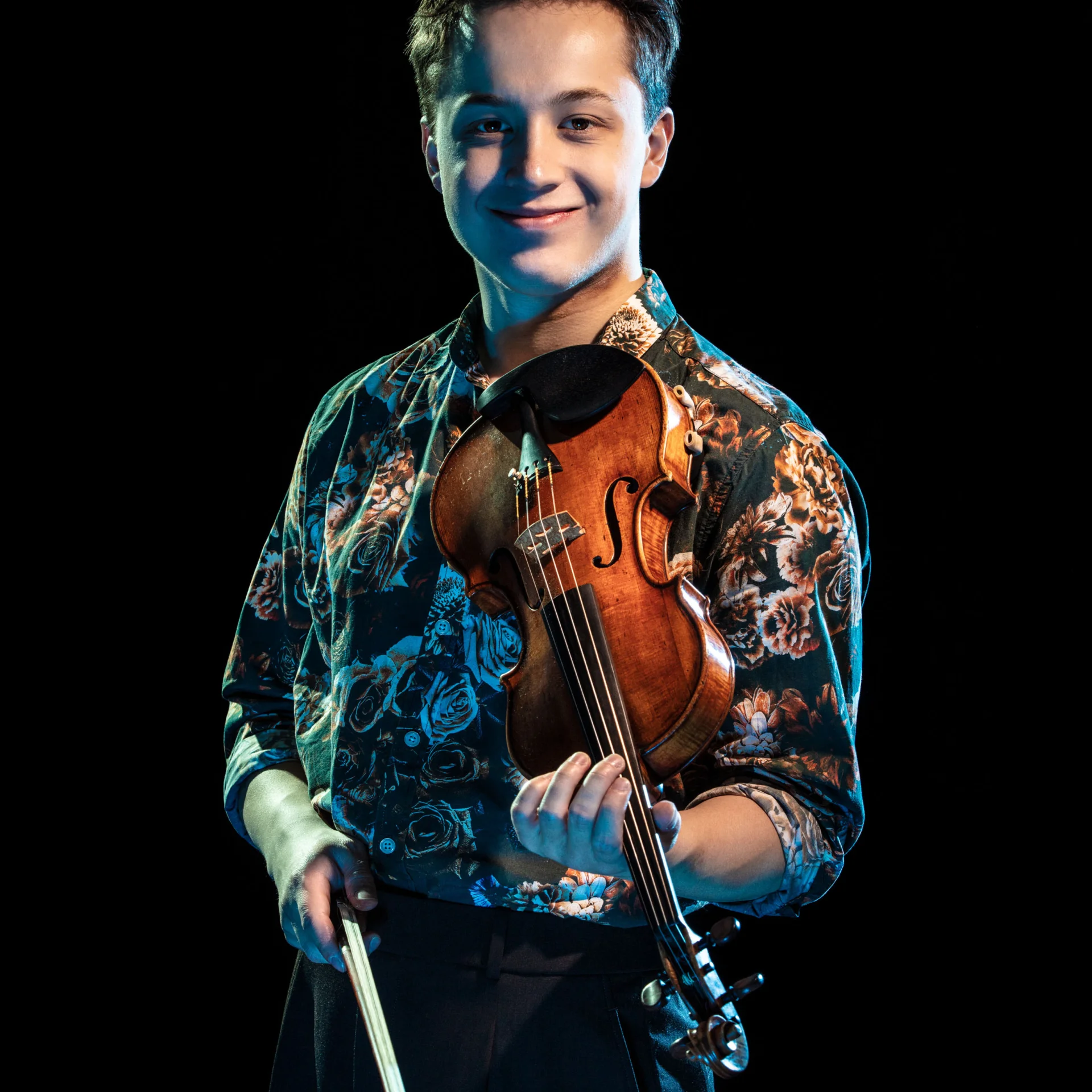 A photo of Johan Dalene looking directly at the camera holing his violin.