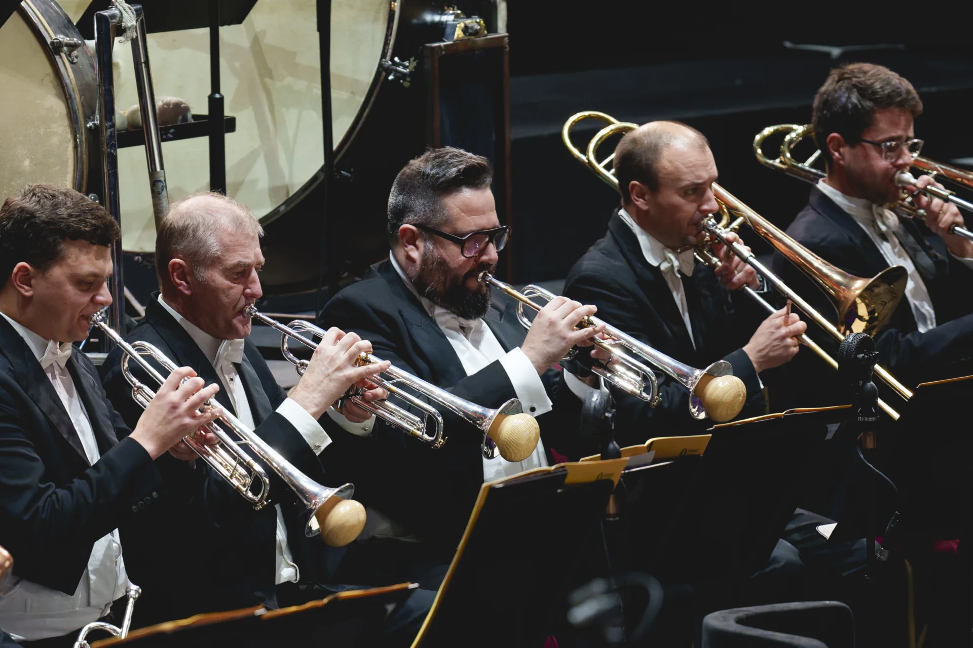 Three trumpet players with mutes and two trombone players play music