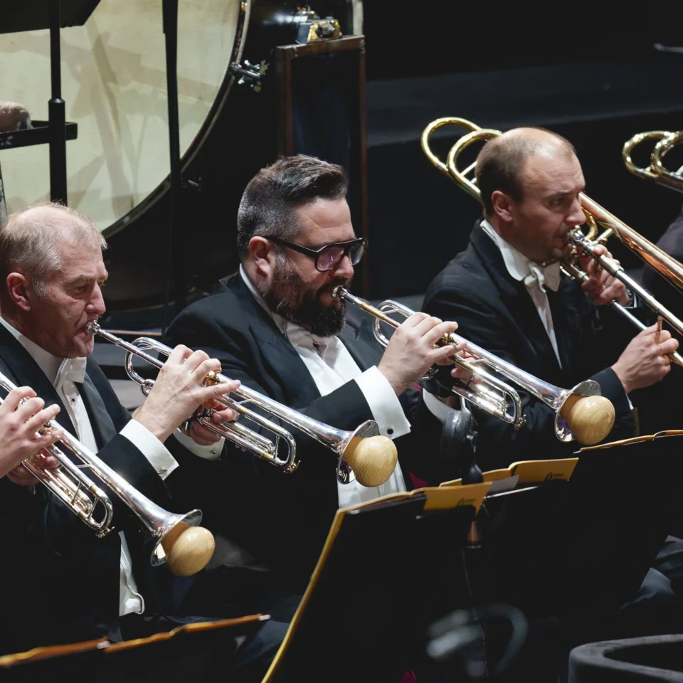 Three trumpet players with mutes and two trombone players play music