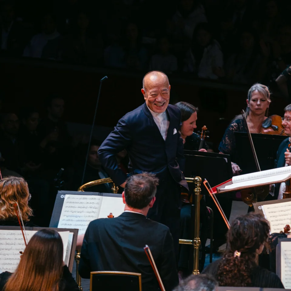 Joe Hisaishi at the podium and smiling at the Orchestra