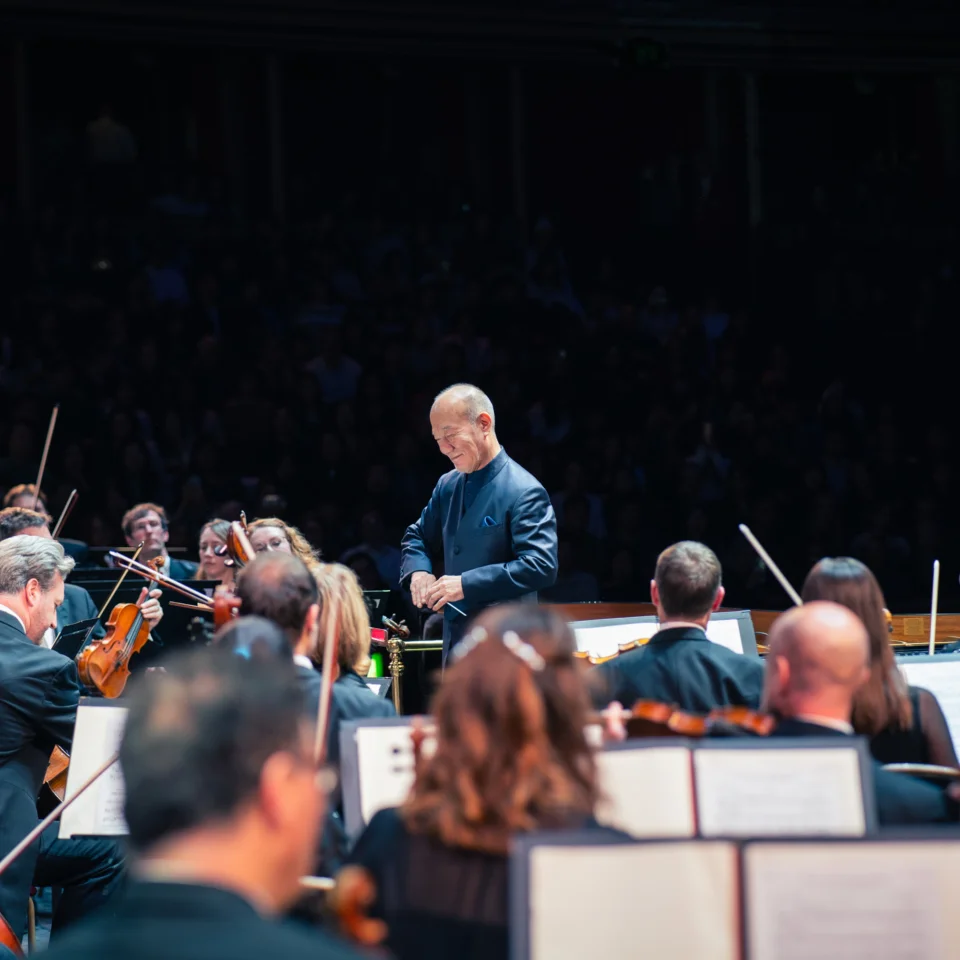 Joe Hisaishi smiling as he is about to conduct the Orchestra