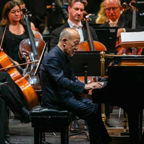 Joe Hisaishi playing the piano in front of the Orchestra