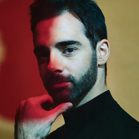 Cellist Pablo Ferrández scratching his chin and looking at the camera