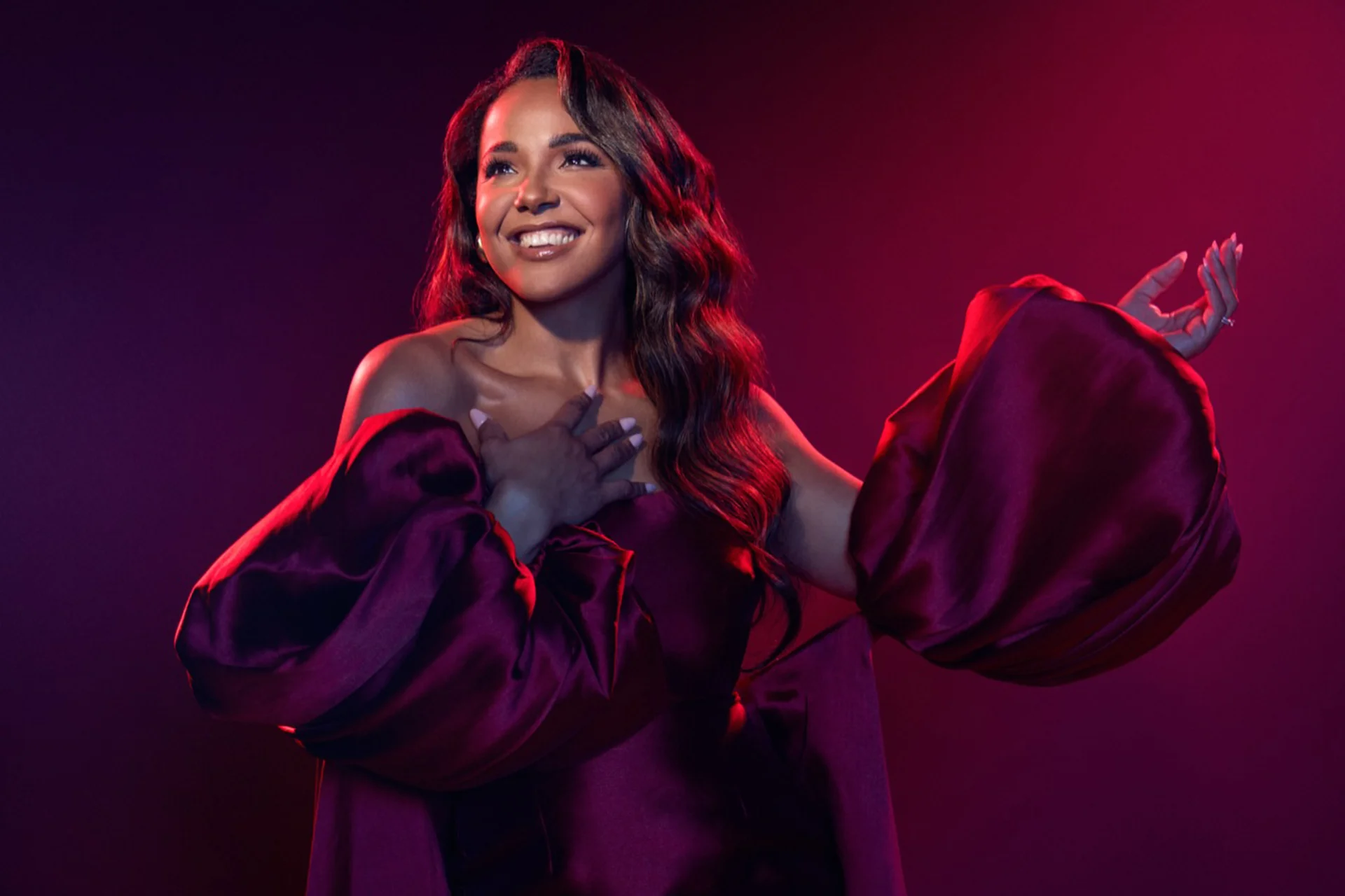 A photo of Shanay Holmes under theatre-style lighting and smiling