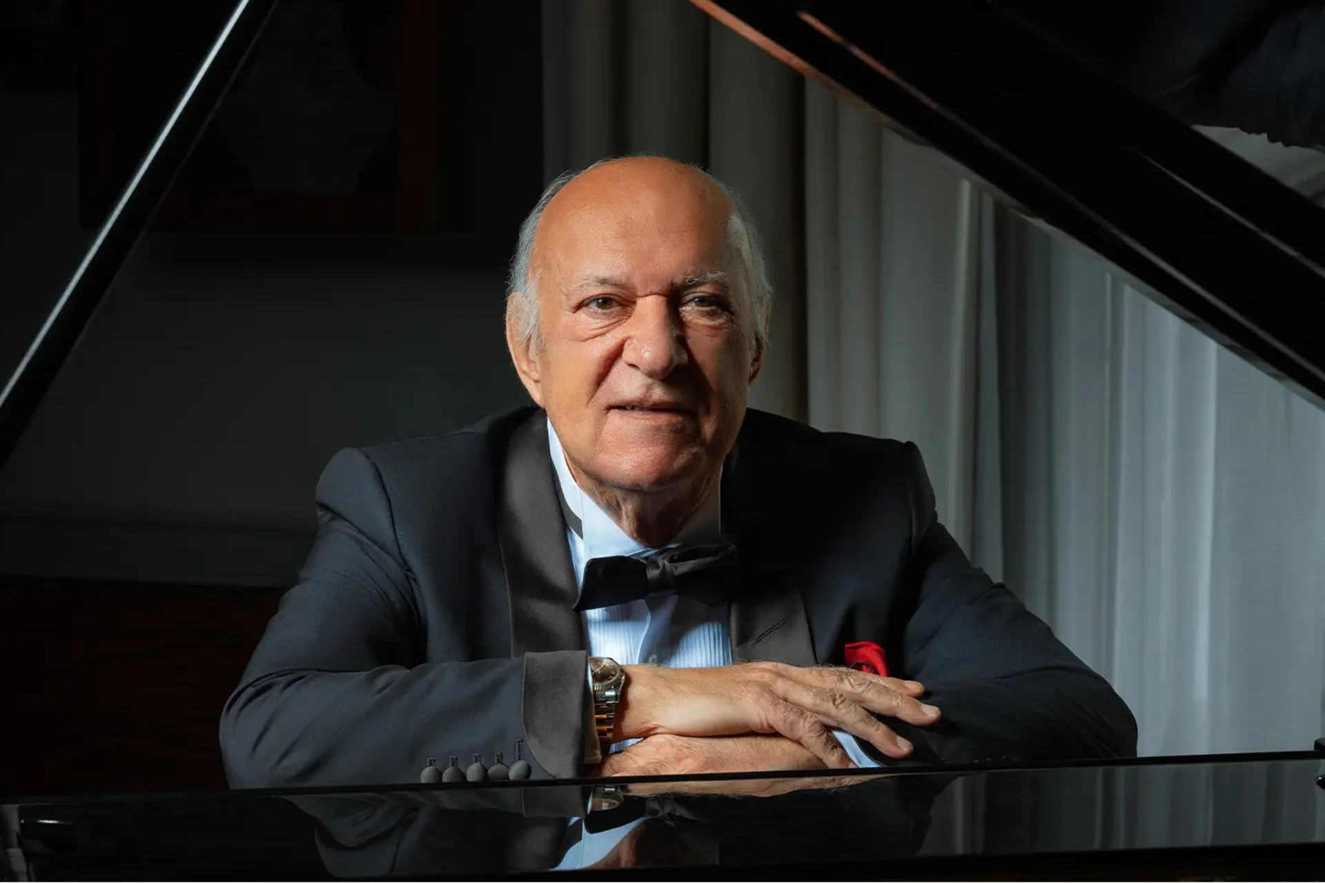 Omar Khairat sitting at a piano with the lid raised