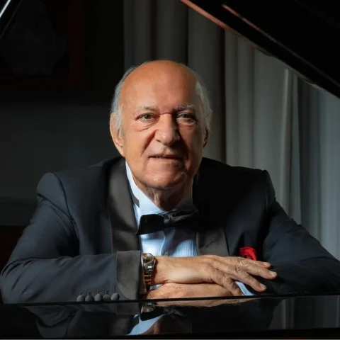 Omar Khairat sitting at a piano with the lid raised