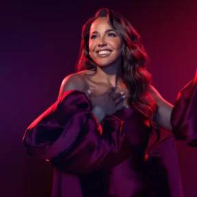 A photo of Shanay Holmes under theatre-style lighting and smiling
