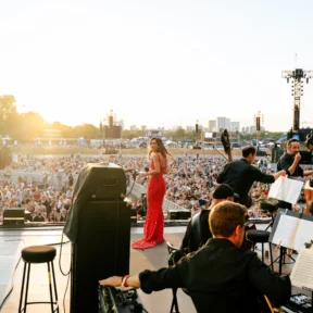 Myleene Klass in a red dress on stage with the Orchestra at BST Hyde Park