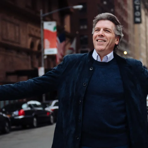 Baritone Thomas Hampson in the middle of a street stretching out his arms