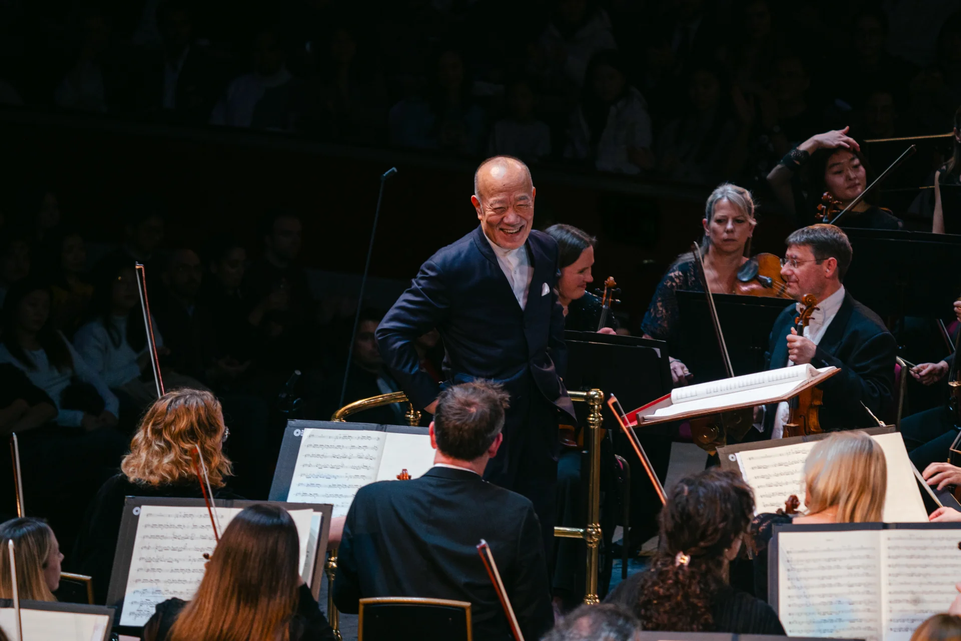 Joe Hisaishi at the podium and smiling at the Orchestra