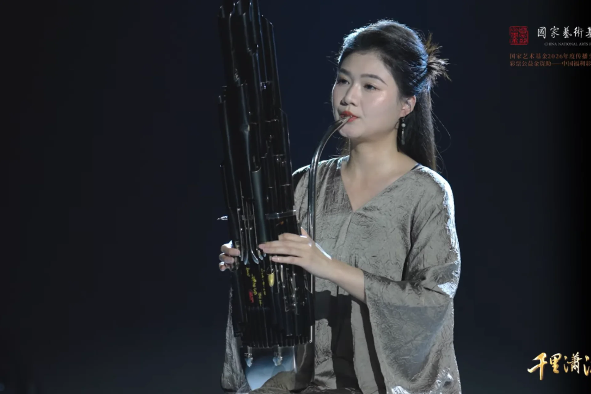 A video thumbnail with a woman playing a traditional instrument