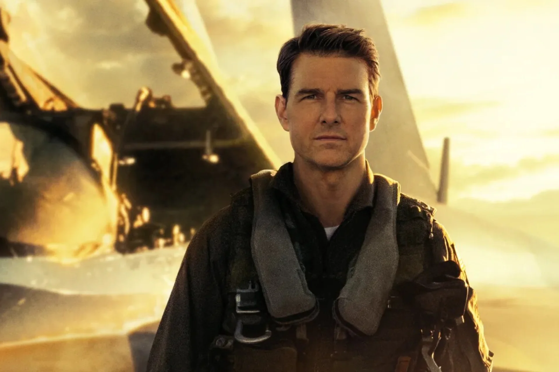 Tom Cruise in character as 'Maverick' standing in front of a fighter jet in the film 'Top Gun'.