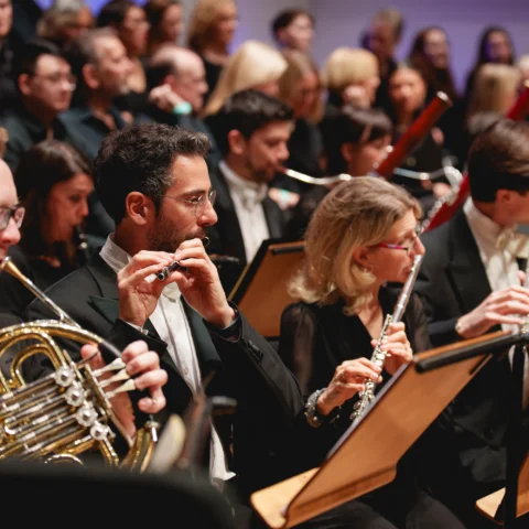 The RPo wind section playing in front of a choir at Cadogan Hall. The piccolo is in focus.