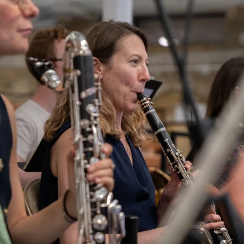 The woodwind section of the Royal Philharmonic Orchestra in rehearsal, smiling while playing