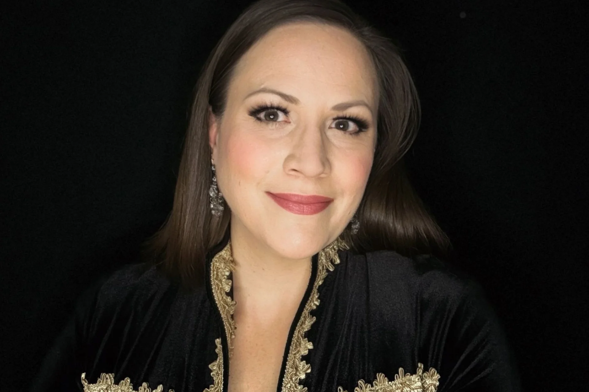 Mezzo-soprano Jennifer Johnston looking into the camera wearing a black and gold jacket