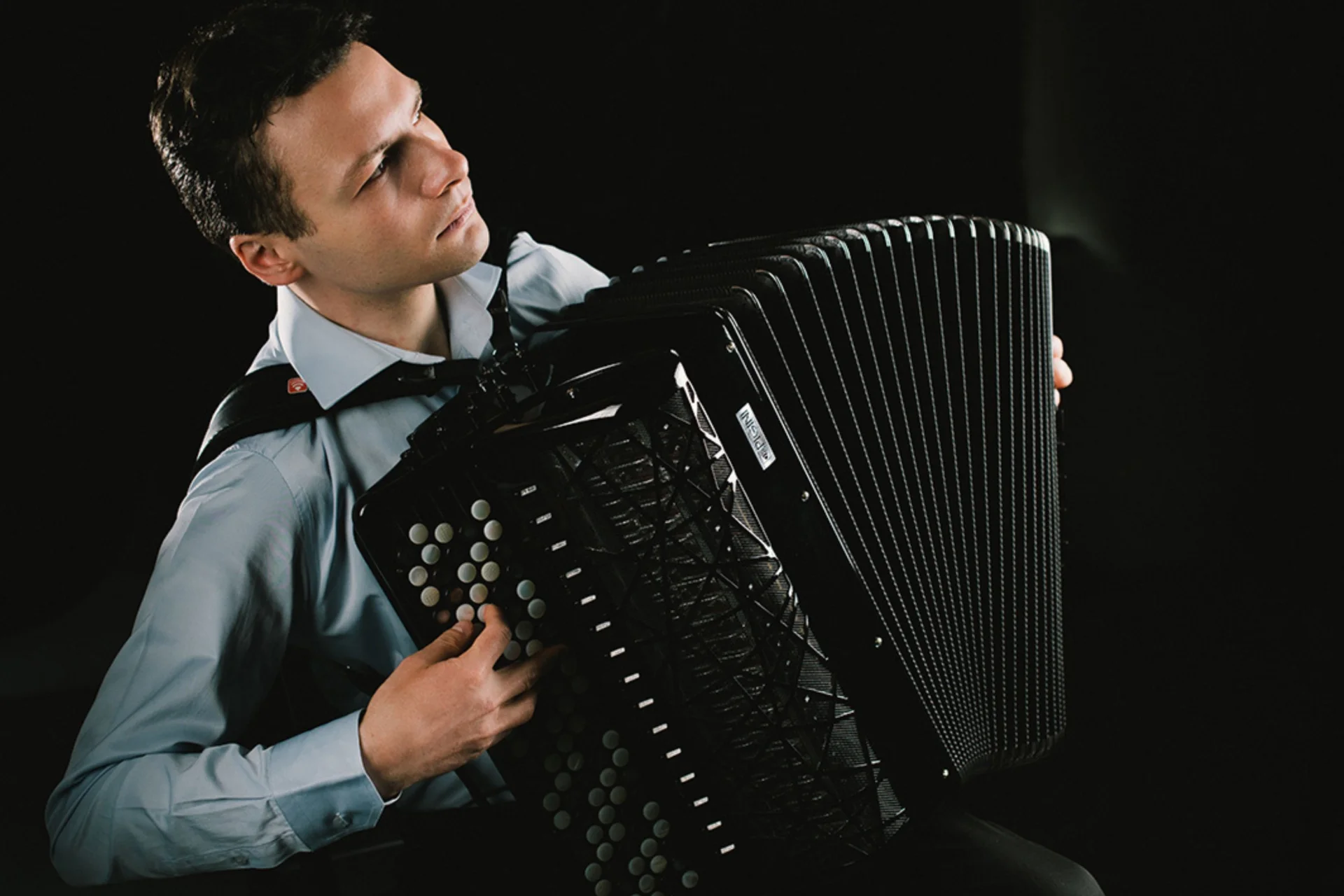 Milos Milivojevic plays his accordion under dramatic contrast lighting