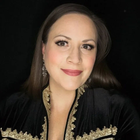 Mezzo-soprano Jennifer Johnston looking into the camera wearing a black and gold jacket