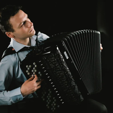 Milos Milivojevic plays his accordion under dramatic contrast lighting